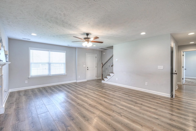unfurnished living room featuring baseboards, wood finished floors, ceiling fan, and stairs