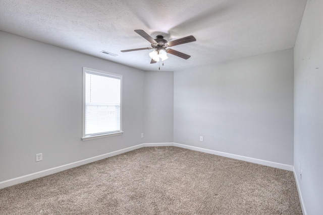 empty room with carpet flooring, a textured ceiling, visible vents, baseboards, and ceiling fan