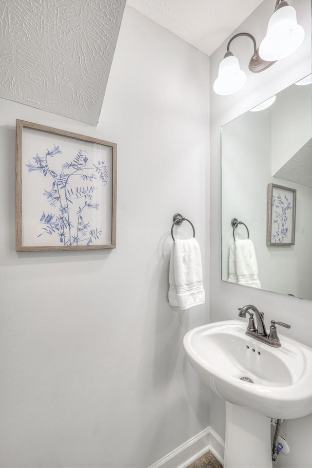 bathroom featuring a sink, baseboards, and a textured ceiling