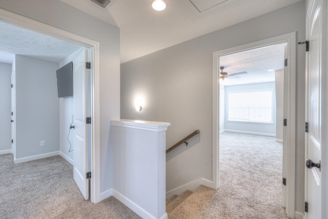 hallway featuring attic access, carpet floors, an upstairs landing, and baseboards
