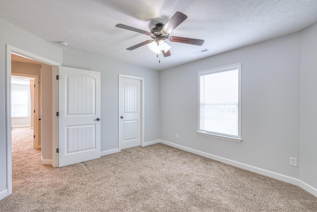 unfurnished bedroom featuring baseboards, visible vents, carpet floors, and a textured ceiling