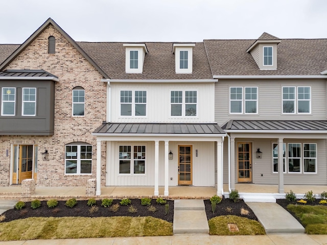 multi unit property with a porch, brick siding, and a shingled roof