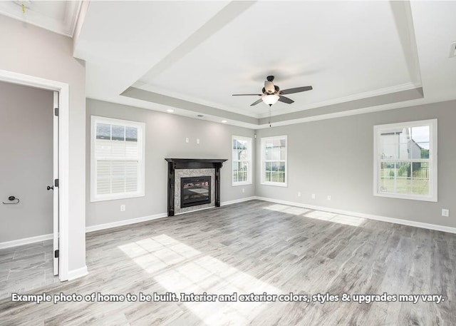 unfurnished living room with plenty of natural light, a tray ceiling, and light wood-type flooring