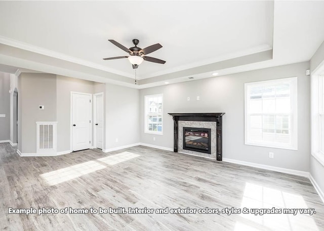 unfurnished living room with crown molding, a fireplace, light hardwood / wood-style floors, and a raised ceiling