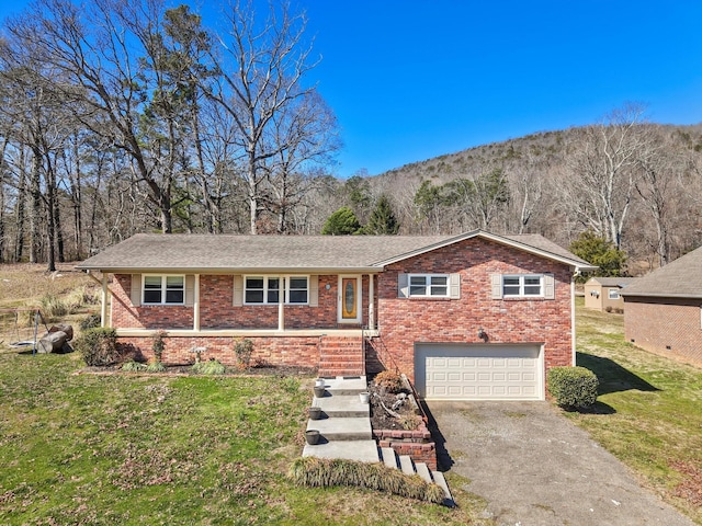 view of front of house featuring a front yard, brick siding, driveway, and an attached garage