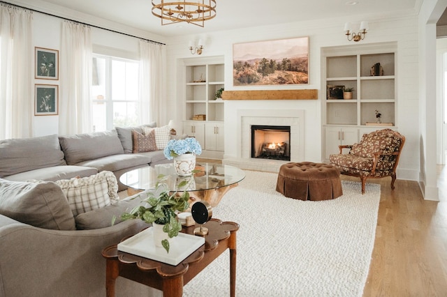 living room with built in shelves, light hardwood / wood-style floors, and a notable chandelier