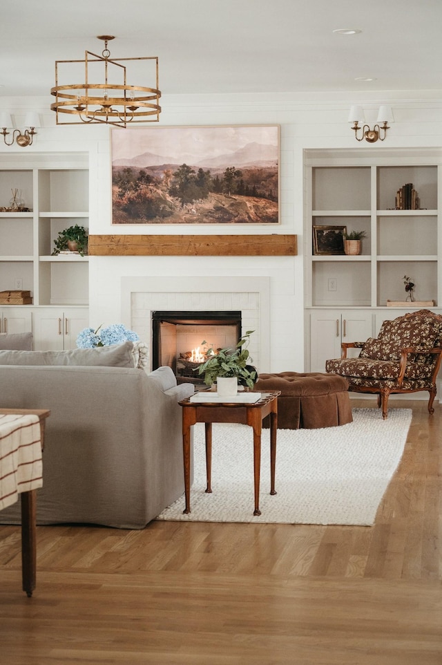 living room featuring hardwood / wood-style flooring, crown molding, built in shelves, and a notable chandelier