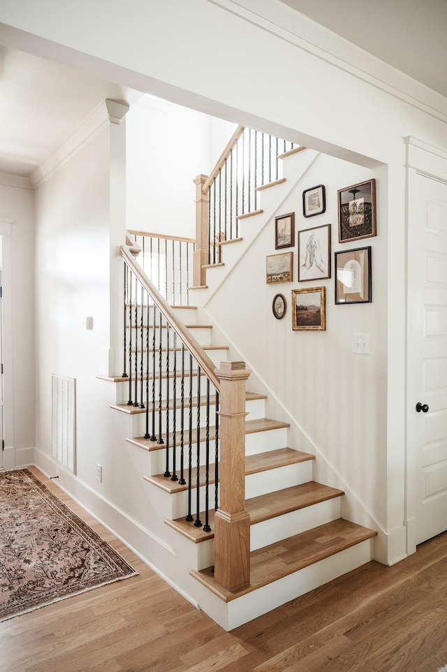 staircase featuring ornamental molding and hardwood / wood-style floors