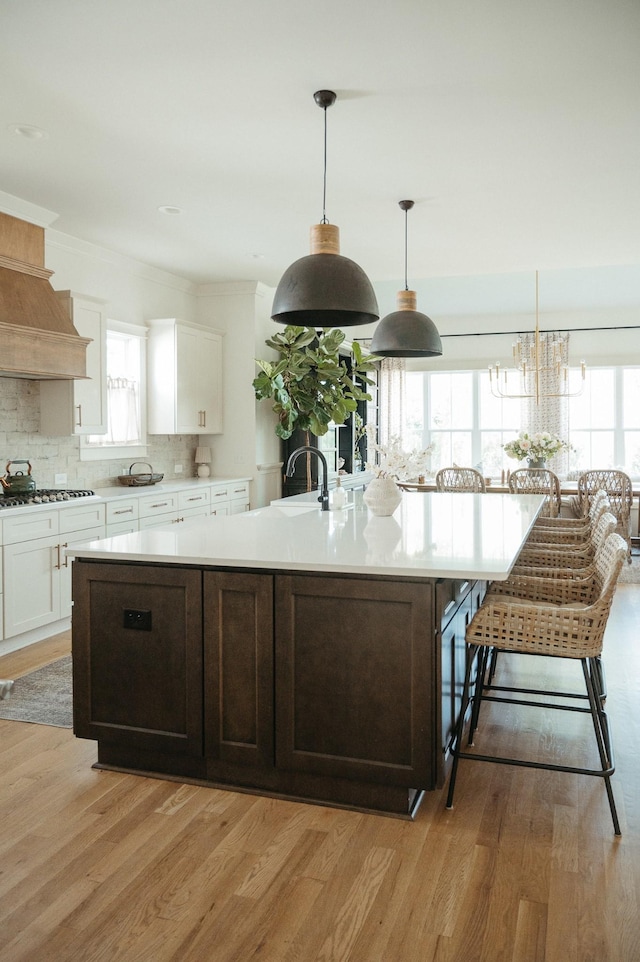 kitchen featuring hanging light fixtures, light wood-type flooring, and a large island with sink