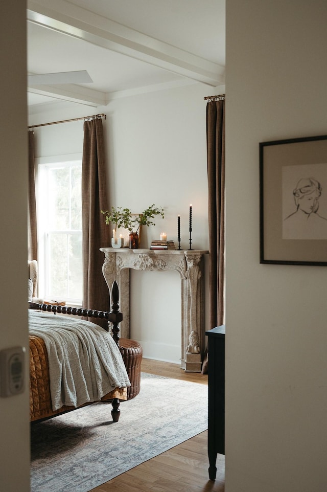 bedroom featuring beam ceiling and light hardwood / wood-style flooring