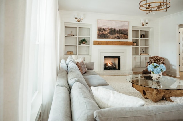 living room with crown molding, a chandelier, and built in shelves