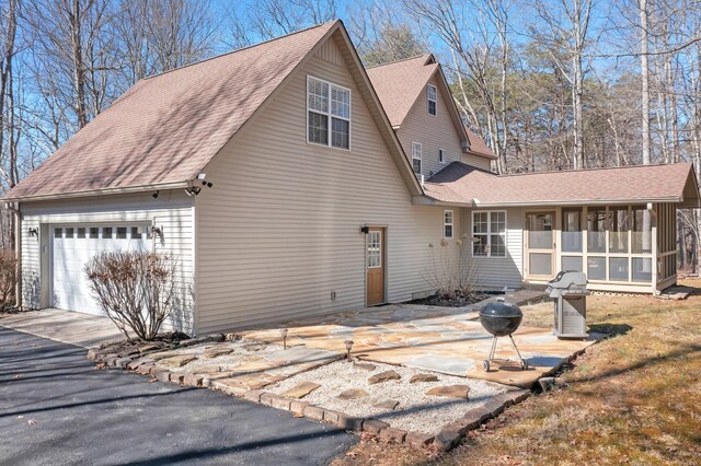 view of side of home featuring a garage, a sunroom, and a patio area