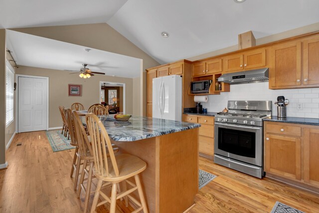 kitchen featuring a center island, a breakfast bar, extractor fan, white fridge, and stainless steel gas range