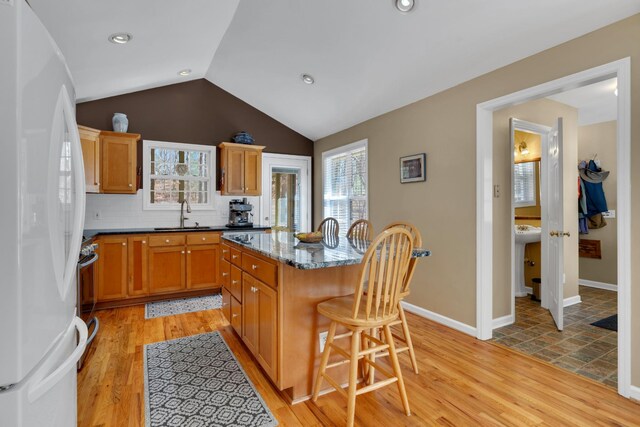 kitchen with a center island, white refrigerator, a breakfast bar, and a wealth of natural light