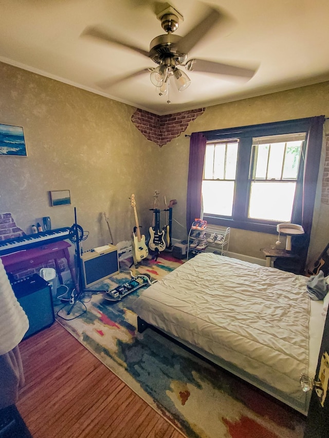 bedroom featuring wood-type flooring, ornamental molding, and ceiling fan