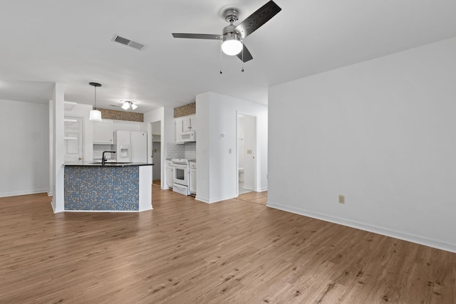 unfurnished living room with ceiling fan, sink, and light wood-type flooring