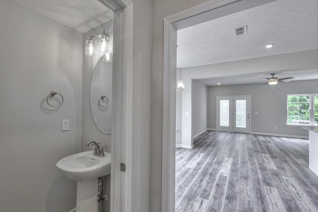 bathroom featuring a textured ceiling, wood finished floors, visible vents, and baseboards