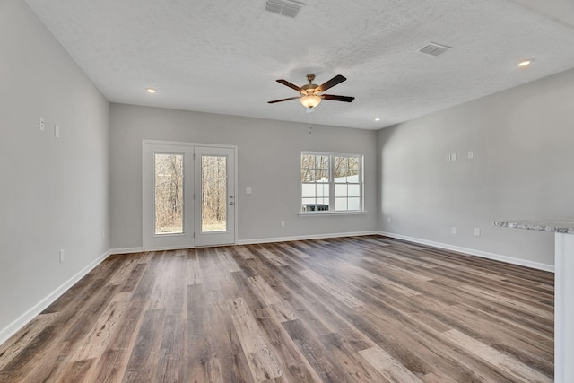 unfurnished room featuring visible vents, dark wood finished floors, a textured ceiling, and baseboards