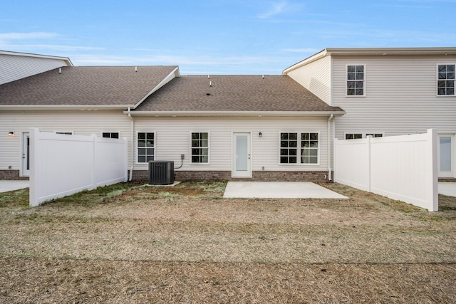 back of house featuring a shingled roof, central AC unit, a patio, fence private yard, and a yard