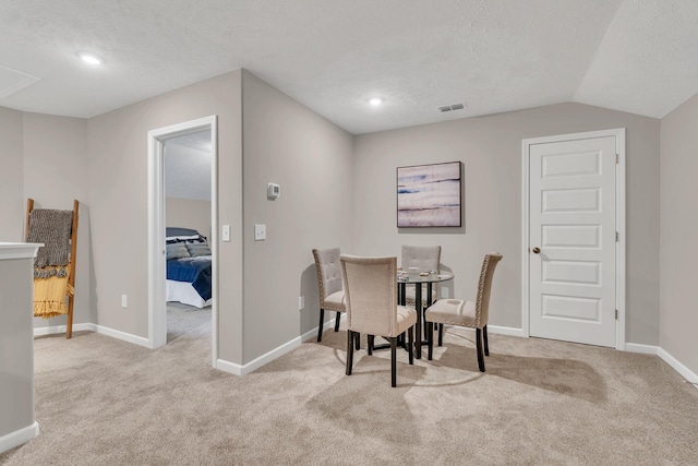 dining space featuring light carpet, a textured ceiling, visible vents, and baseboards