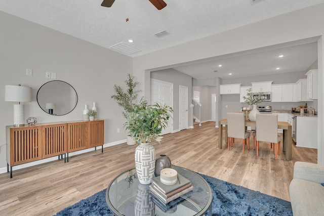 living room with light wood finished floors, recessed lighting, a ceiling fan, and baseboards