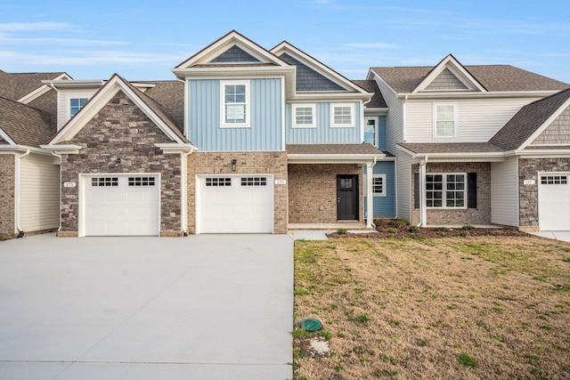 view of front of house featuring board and batten siding, a front yard, brick siding, and driveway