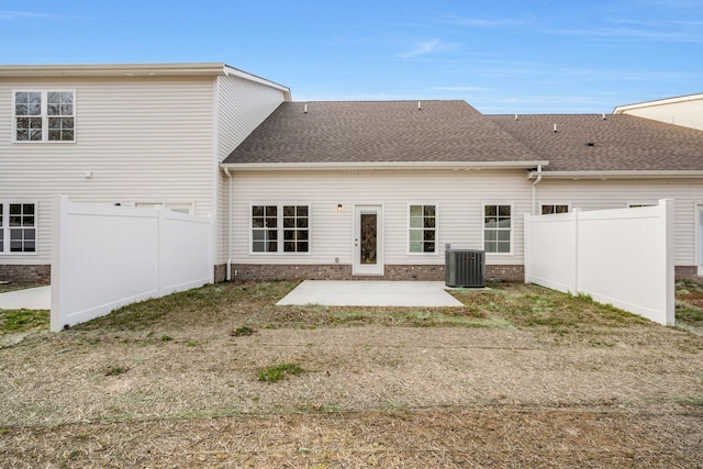 back of property with central AC, roof with shingles, a patio area, and fence