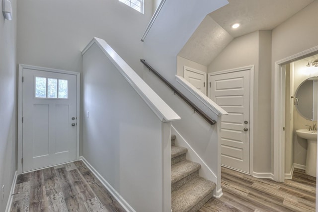 foyer with recessed lighting, vaulted ceiling, wood finished floors, baseboards, and stairs