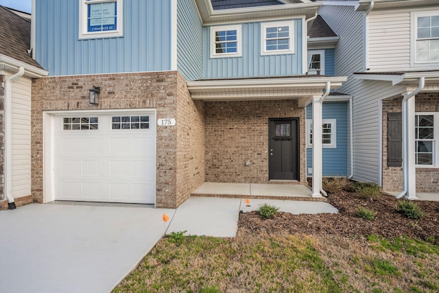 view of front of house with board and batten siding, concrete driveway, brick siding, and a garage