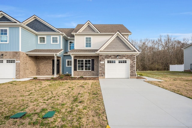 view of front of home featuring a garage, driveway, a shingled roof, and a front yard