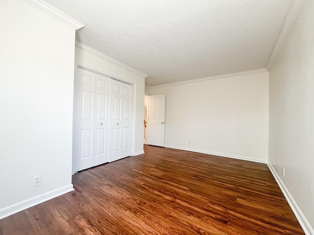 unfurnished bedroom featuring crown molding, dark hardwood / wood-style floors, and a closet