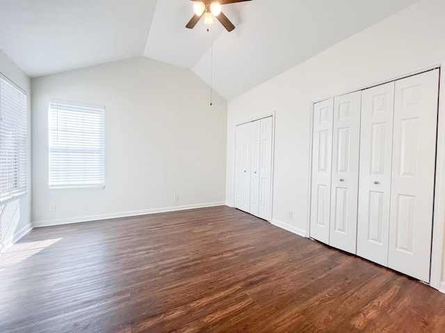 unfurnished bedroom featuring vaulted ceiling, dark hardwood / wood-style floors, two closets, and ceiling fan