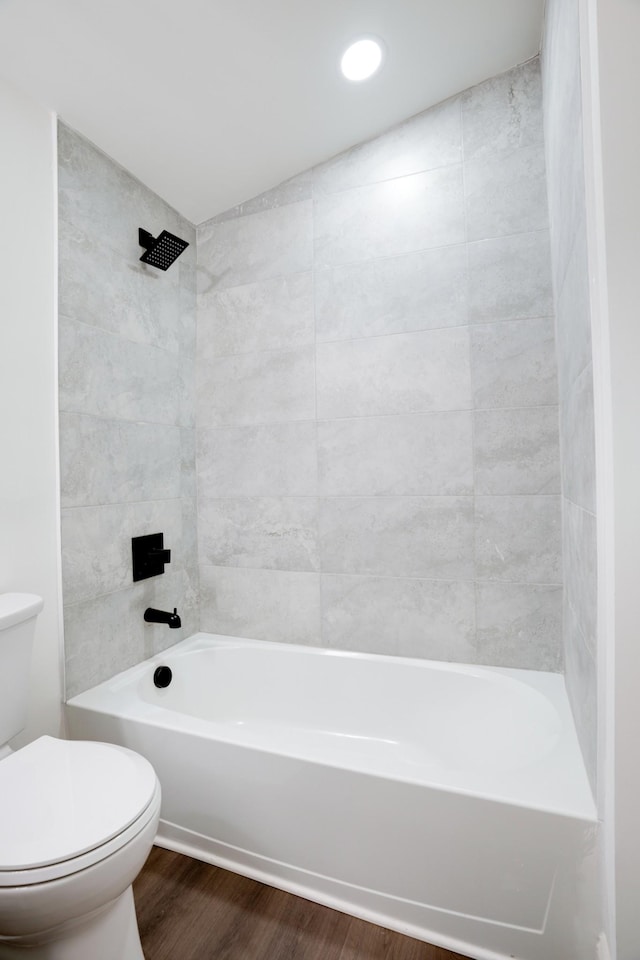 bathroom with hardwood / wood-style floors, tiled shower / bath combo, and toilet