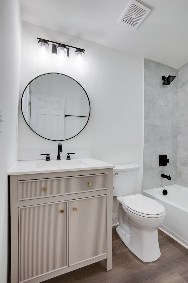 full bathroom with vanity, tiled shower / bath combo, toilet, and hardwood / wood-style flooring