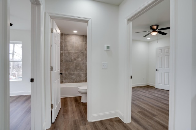 bathroom featuring ceiling fan, tiled shower / bath combo, wood-type flooring, and toilet