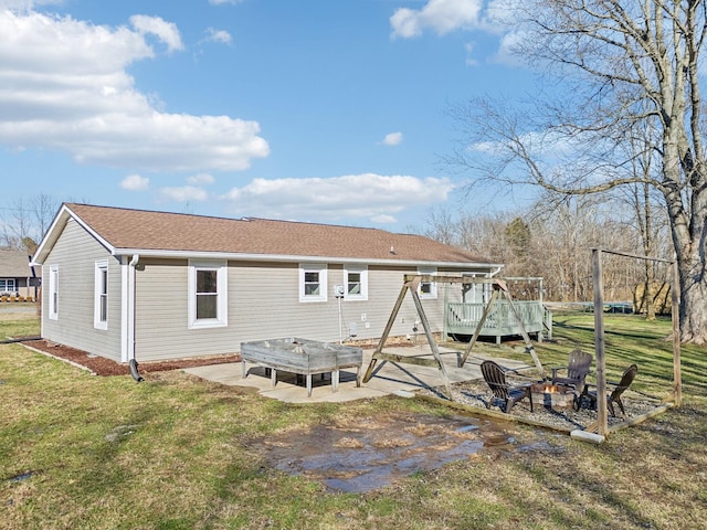 rear view of property featuring a patio area, a fire pit, a deck, and a lawn