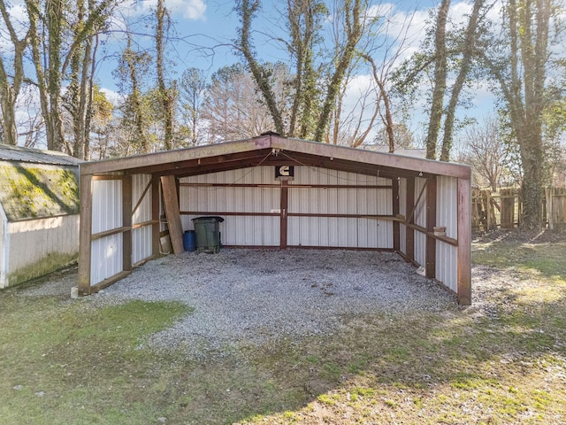 view of pole building featuring driveway and fence