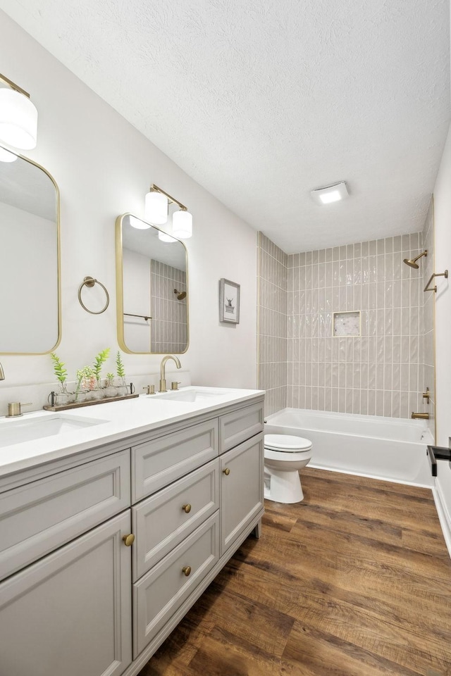 bathroom with double vanity,  shower combination, wood finished floors, and a sink