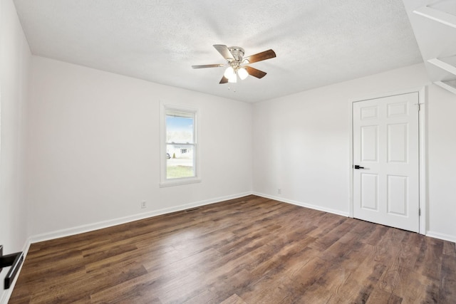 unfurnished room with ceiling fan, baseboards, dark wood finished floors, and a textured ceiling