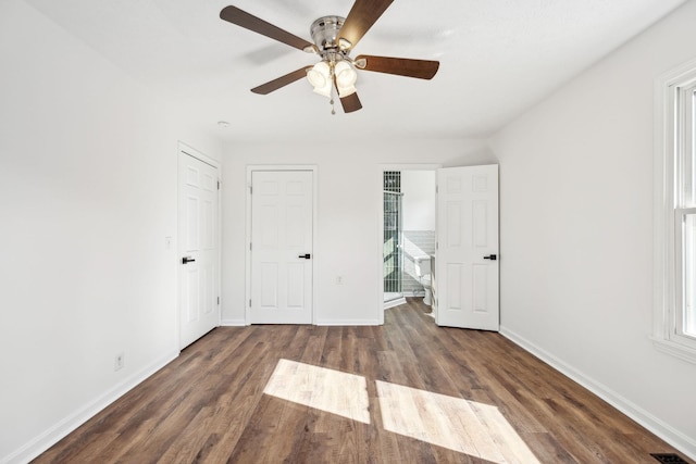 unfurnished bedroom featuring a ceiling fan, dark wood-style flooring, visible vents, and baseboards