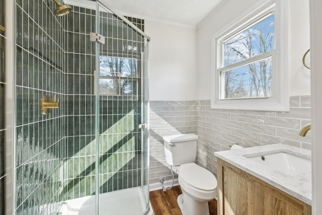 bathroom featuring tile walls, toilet, a stall shower, vanity, and wood finished floors