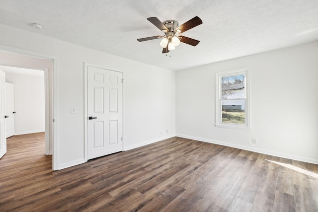 unfurnished bedroom featuring dark wood-type flooring, a textured ceiling, baseboards, and a ceiling fan
