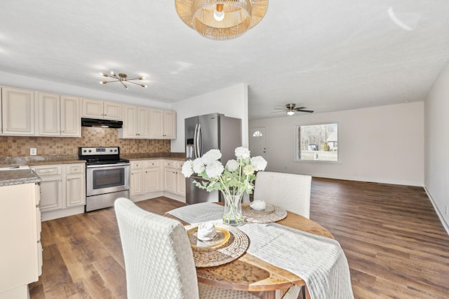 kitchen with decorative backsplash, appliances with stainless steel finishes, open floor plan, wood finished floors, and under cabinet range hood