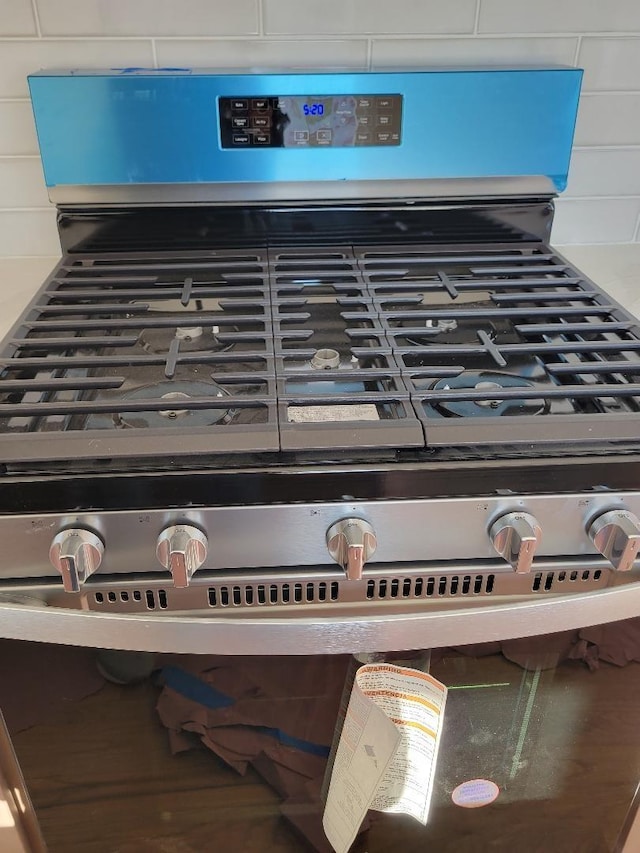 room details featuring decorative backsplash and stainless steel gas range oven