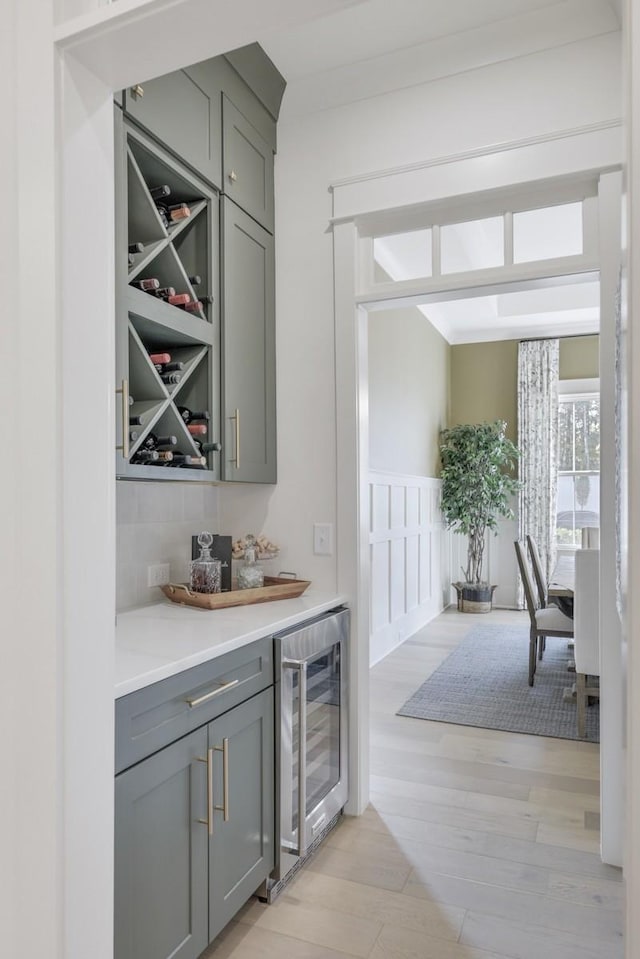 bar featuring gray cabinetry, wine cooler, and light hardwood / wood-style flooring