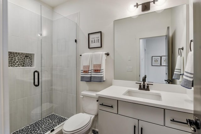 bathroom featuring vanity, toilet, and a shower with shower door