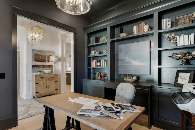 office space featuring light wood-type flooring, a chandelier, and built in shelves