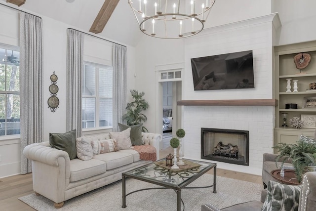 living room with beam ceiling, a brick fireplace, and light wood-type flooring