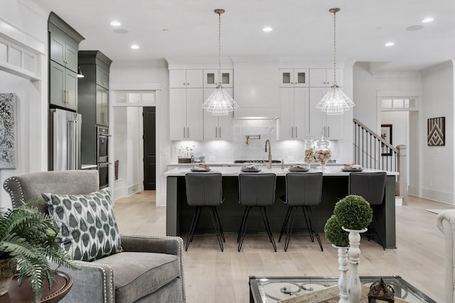 kitchen featuring stainless steel appliances, a center island with sink, decorative backsplash, and decorative light fixtures