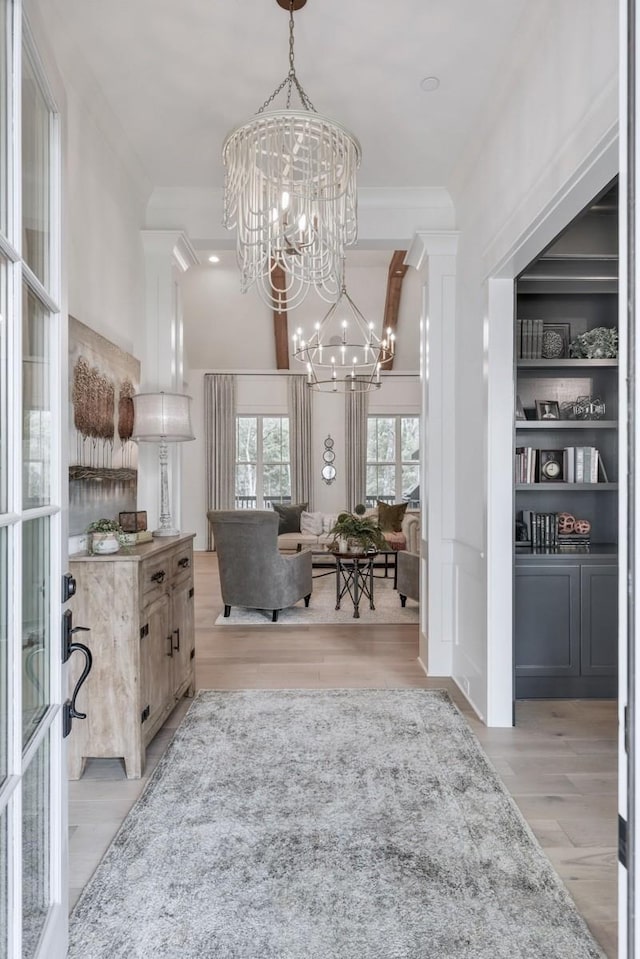 interior space with a notable chandelier, crown molding, built in features, and light wood-type flooring